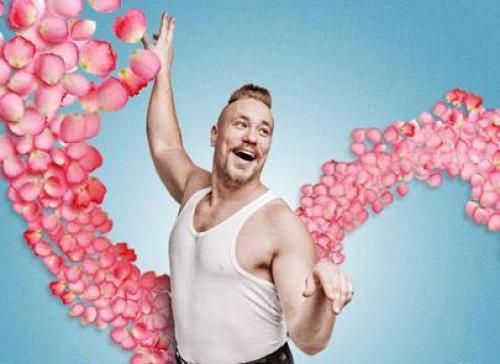 A man wearing a sleeveless shirt dancing in a flower petal rain